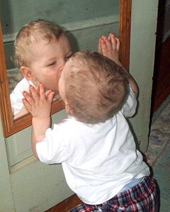 baby kissing a mirror